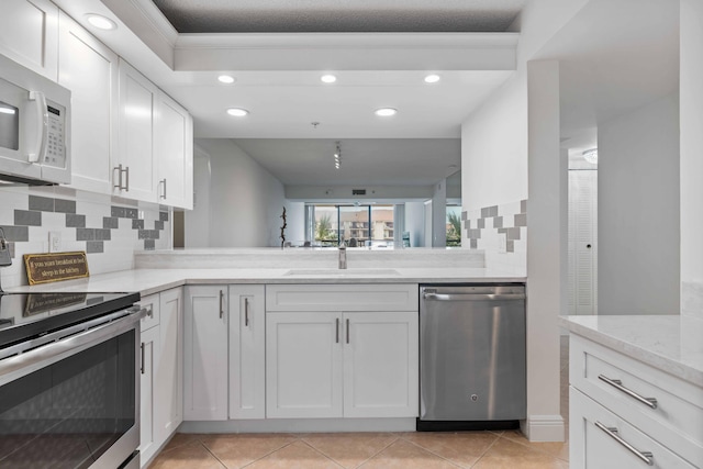 kitchen with sink, stainless steel appliances, white cabinets, and tasteful backsplash