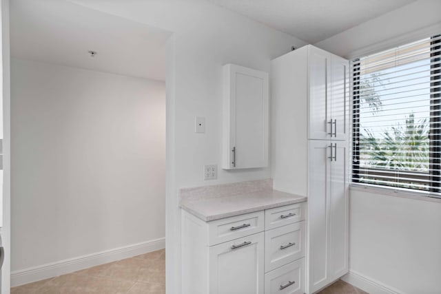 kitchen featuring white cabinetry, light tile floors, and light stone counters