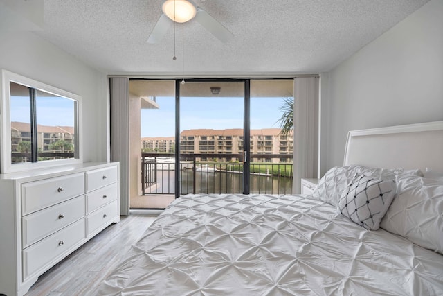 bedroom with access to exterior, light hardwood / wood-style floors, a textured ceiling, and ceiling fan