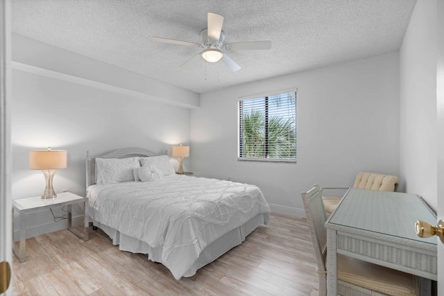 bedroom with a textured ceiling, ceiling fan, and light hardwood / wood-style flooring