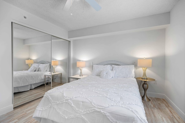 bedroom with a textured ceiling, a closet, light hardwood / wood-style floors, and ceiling fan