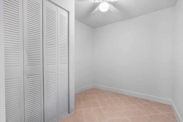 tiled empty room featuring ceiling fan and a textured ceiling