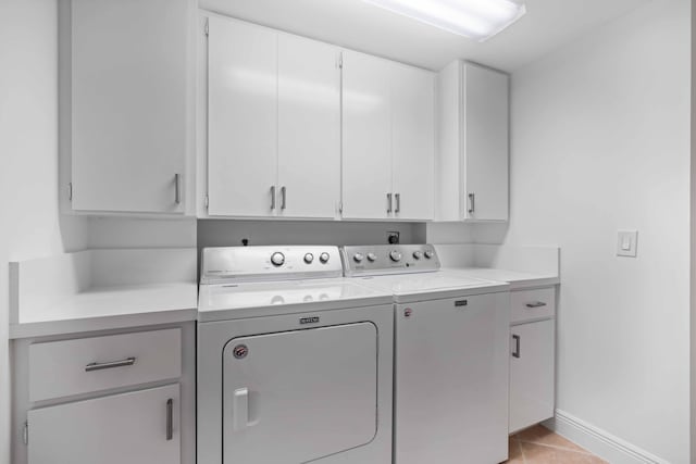 clothes washing area with independent washer and dryer, cabinets, and light tile floors