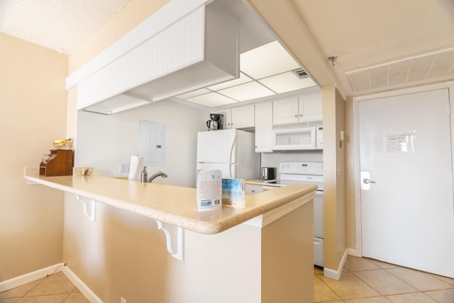 kitchen featuring kitchen peninsula, white appliances, white cabinets, a breakfast bar, and light tile flooring