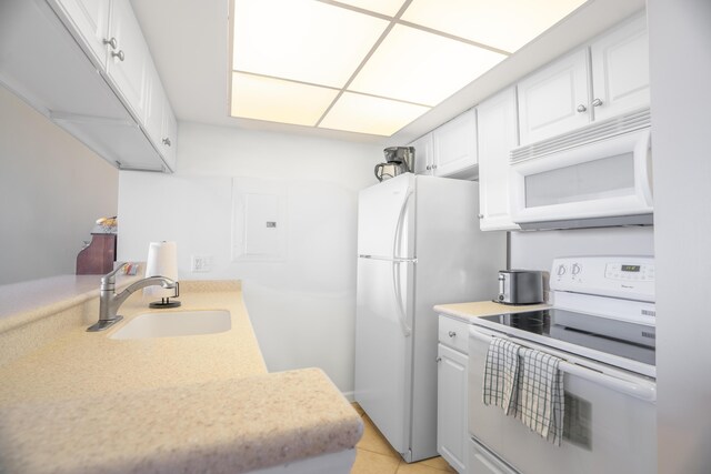 kitchen featuring white appliances, white cabinetry, light countertops, and a sink