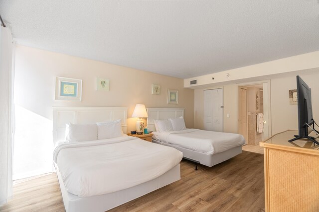 bedroom featuring access to outside, a textured ceiling, floor to ceiling windows, and light wood-type flooring