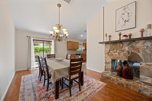 dining space featuring a notable chandelier, a fireplace, and hardwood / wood-style flooring