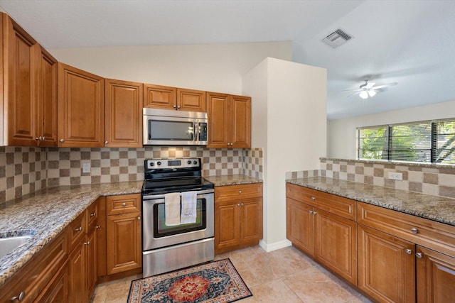 kitchen featuring backsplash, stainless steel appliances, ceiling fan, and light stone counters