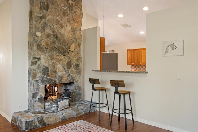 living room featuring a textured ceiling, a fireplace, and dark wood-type flooring