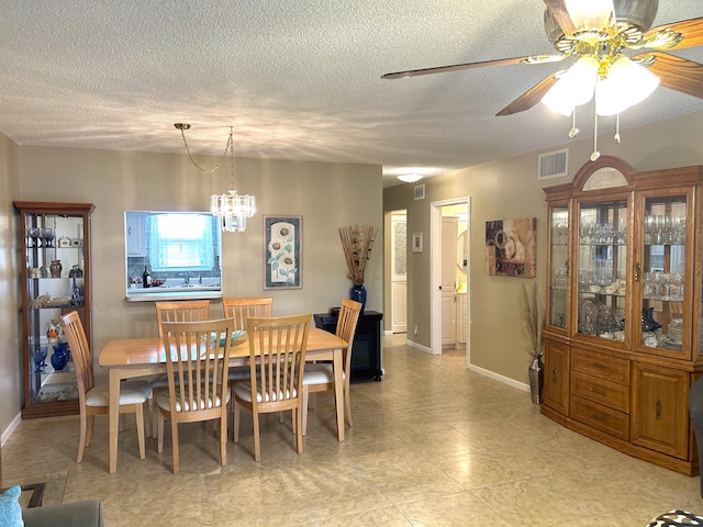 dining room with a textured ceiling, ceiling fan with notable chandelier, and light tile floors