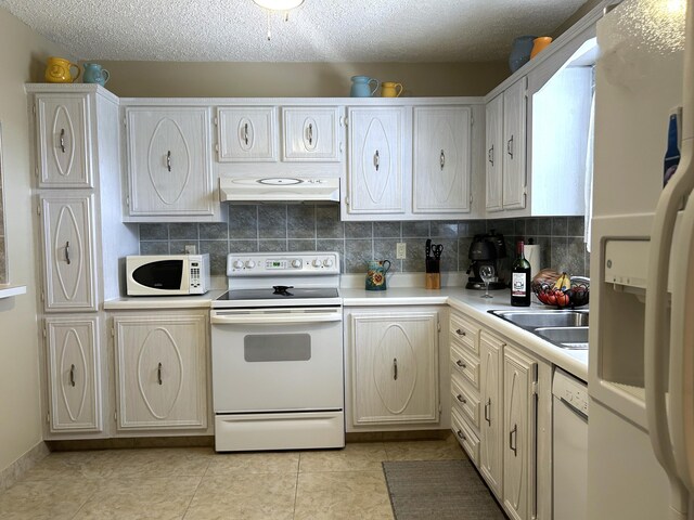 kitchen with light tile flooring, tasteful backsplash, white appliances, and sink