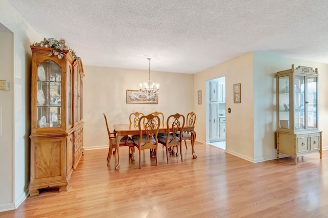 dining room with an inviting chandelier, a textured ceiling, and light hardwood / wood-style flooring