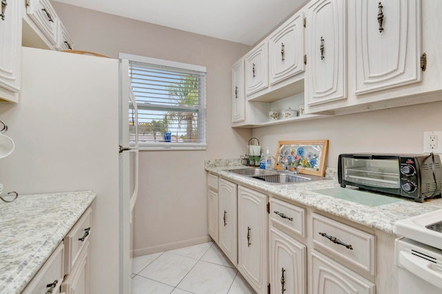 kitchen featuring light stone countertops, white cabinets, sink, and light tile floors