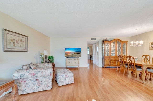 living room featuring a textured ceiling, a chandelier, and light hardwood / wood-style flooring