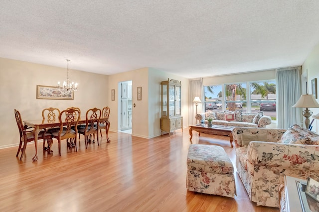 living room featuring an inviting chandelier, a textured ceiling, and light hardwood / wood-style flooring