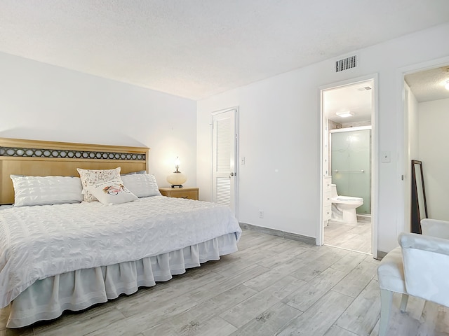 bedroom featuring ensuite bath, a closet, and light hardwood / wood-style flooring