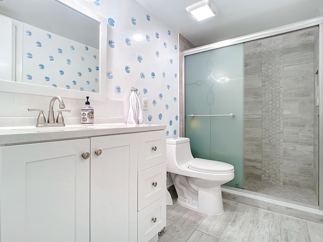 bathroom featuring toilet, tasteful backsplash, a shower with shower door, and vanity