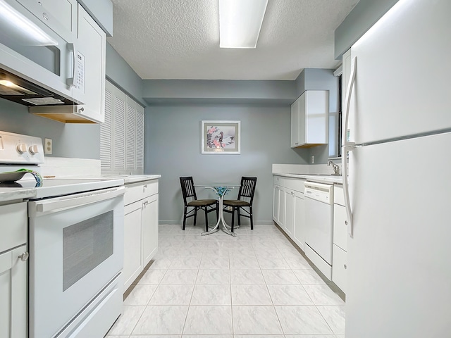 kitchen with white appliances, white cabinetry, a textured ceiling, and light tile flooring