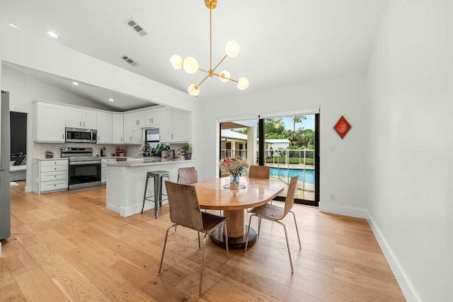 dining area featuring a chandelier, vaulted ceiling, and light hardwood / wood-style flooring