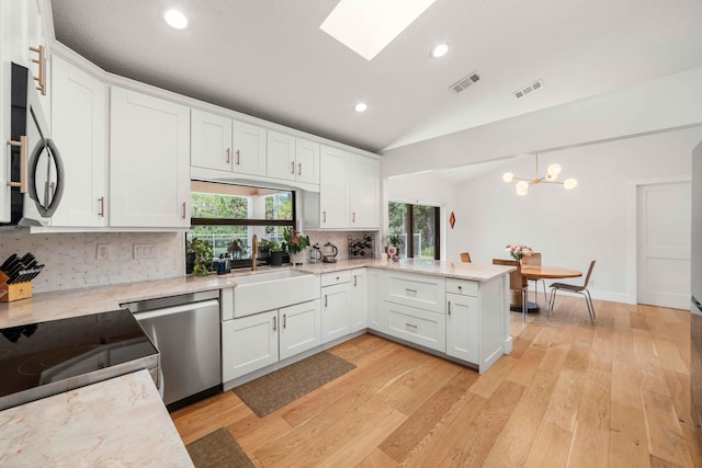 kitchen featuring white cabinetry, light hardwood / wood-style flooring, lofted ceiling with skylight, decorative backsplash, and appliances with stainless steel finishes