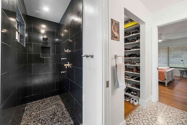 bathroom featuring tiled shower, ceiling fan, and hardwood / wood-style flooring