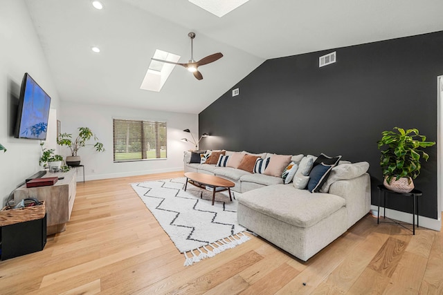 living room featuring lofted ceiling with skylight, ceiling fan, and light hardwood / wood-style floors