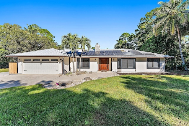 ranch-style house with solar panels, a garage, and a front yard