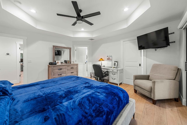 bedroom with a tray ceiling, ceiling fan, and light hardwood / wood-style floors