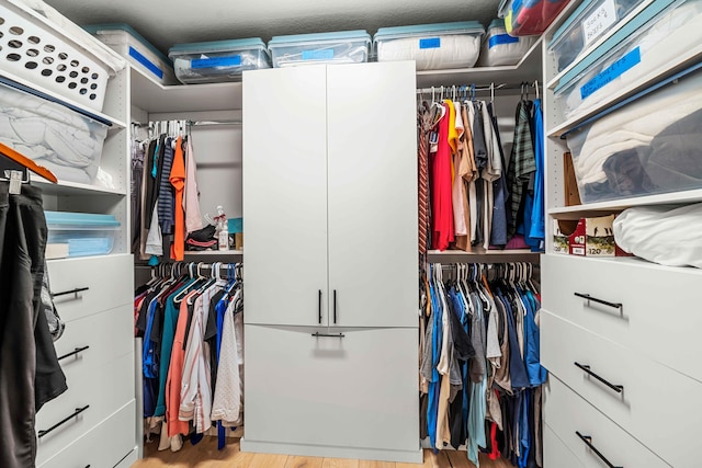 walk in closet with light hardwood / wood-style flooring