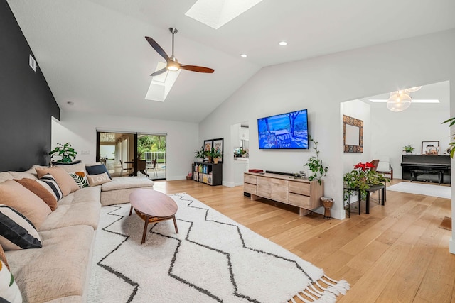 living room with a skylight, ceiling fan, high vaulted ceiling, and light hardwood / wood-style floors