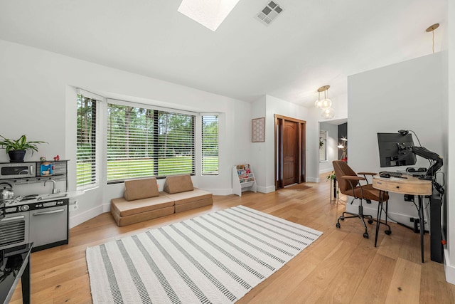 office space with a chandelier, a skylight, and light hardwood / wood-style flooring