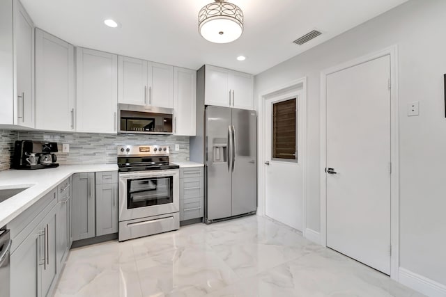 kitchen featuring backsplash, gray cabinetry, stainless steel appliances, and light tile floors