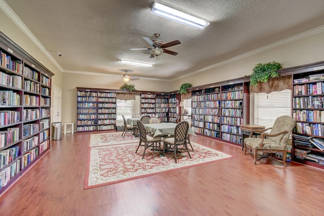 dining room with a textured ceiling, ornamental molding, ceiling fan, and wood-type flooring