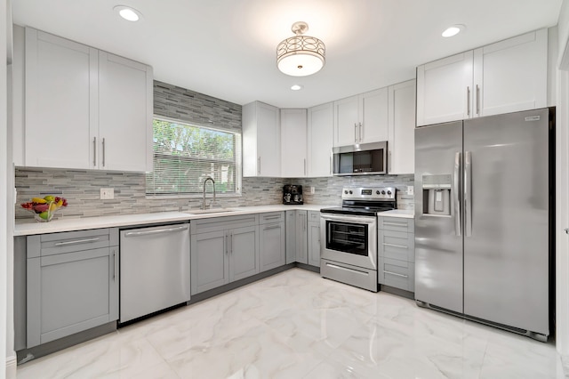 kitchen featuring gray cabinetry, tasteful backsplash, light tile floors, and appliances with stainless steel finishes