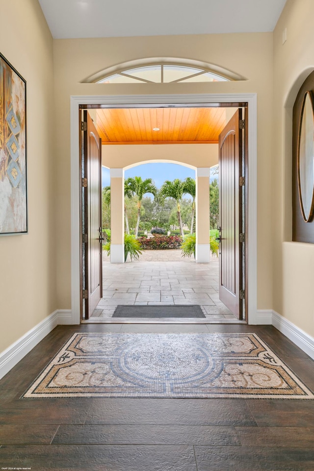 doorway to outside with dark hardwood / wood-style flooring, wooden ceiling, and a wealth of natural light