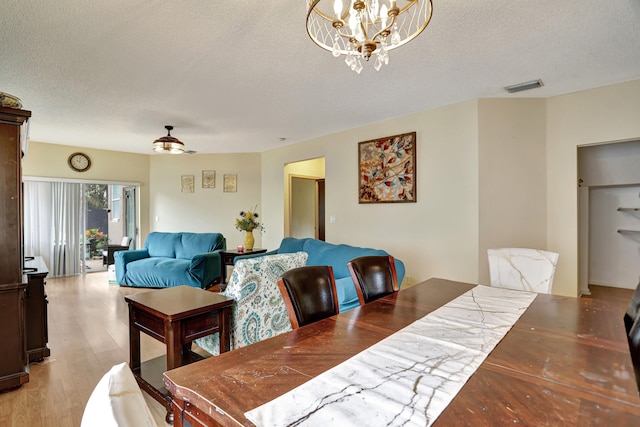 dining area featuring a textured ceiling, ceiling fan with notable chandelier, and light hardwood / wood-style flooring