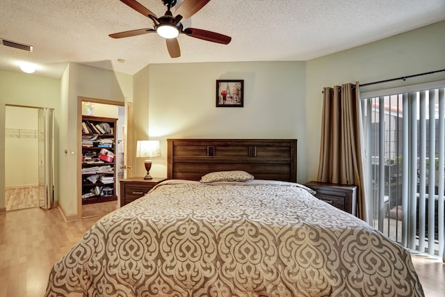 bedroom with light hardwood / wood-style flooring, a textured ceiling, a walk in closet, and a closet