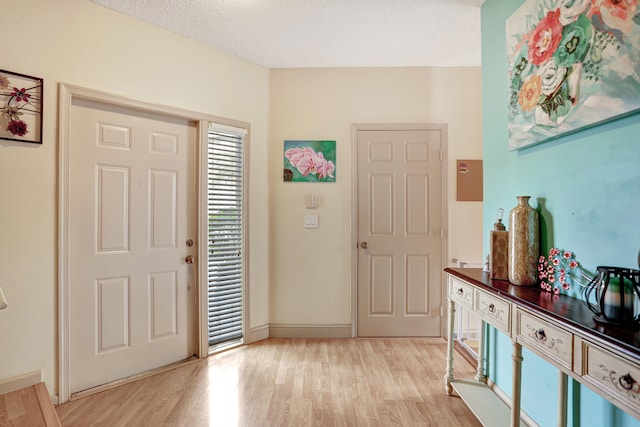 foyer entrance with light wood-type flooring and a textured ceiling