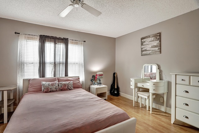 bedroom with a textured ceiling, ceiling fan, and light hardwood / wood-style flooring