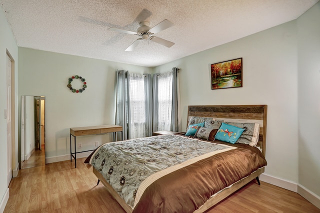 bedroom with light wood-type flooring, a textured ceiling, and ceiling fan