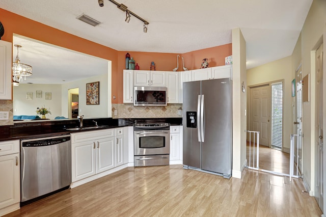 kitchen with stainless steel appliances, white cabinetry, and sink