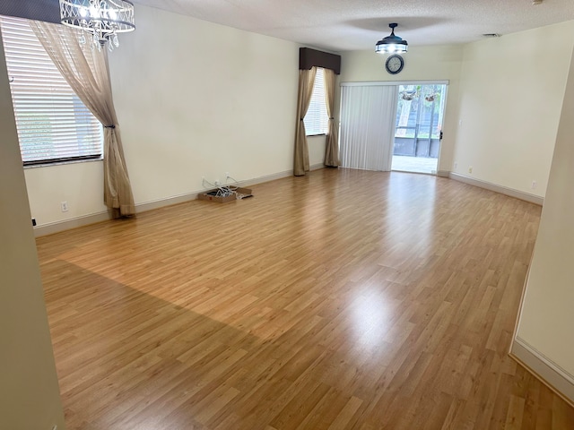 spare room featuring hardwood / wood-style floors, a notable chandelier, and a textured ceiling