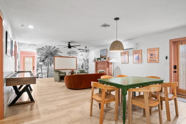 dining area featuring plenty of natural light, an AC wall unit, ceiling fan, and light wood-type flooring