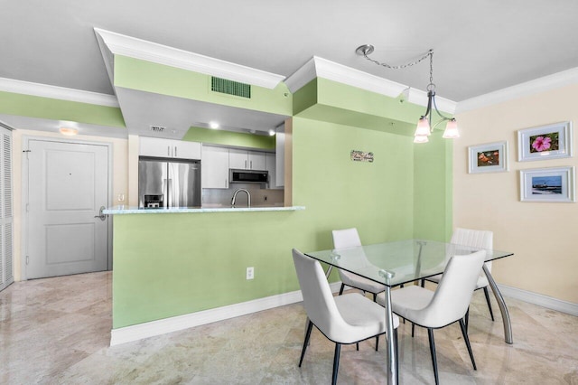 dining space featuring ornamental molding, sink, and an inviting chandelier