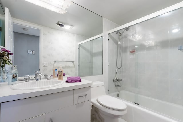 full bathroom featuring vanity, shower / bath combination with glass door, and toilet