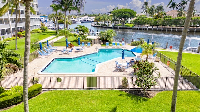 view of pool featuring a lawn, a patio area, and a water view