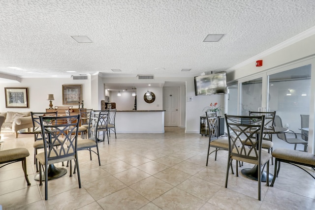 dining space with a textured ceiling, ornamental molding, and light tile floors