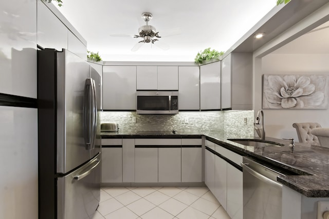 kitchen with sink, ceiling fan, dark stone counters, backsplash, and stainless steel appliances