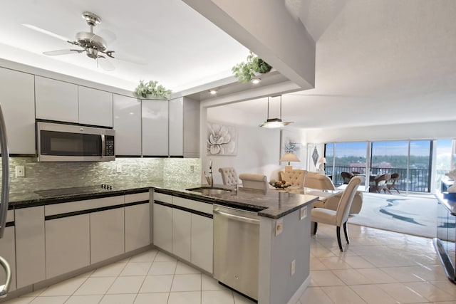 kitchen featuring ceiling fan, sink, dark stone countertops, stainless steel appliances, and light tile flooring