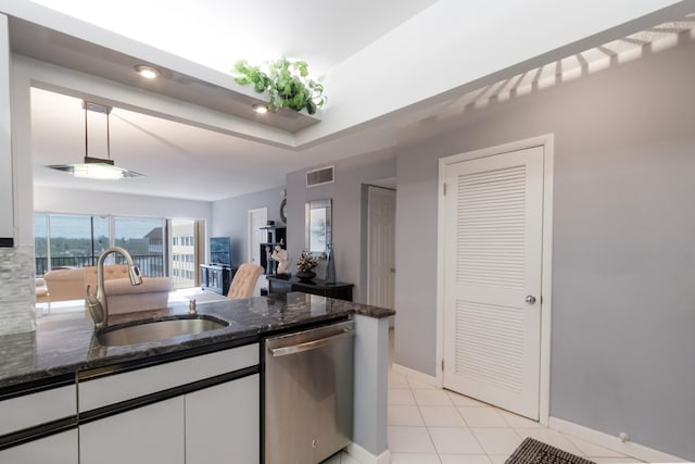 kitchen with dark stone countertops, white cabinets, dishwasher, and sink